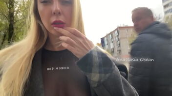 A girl exposes her breasts while she is on the street in the city.